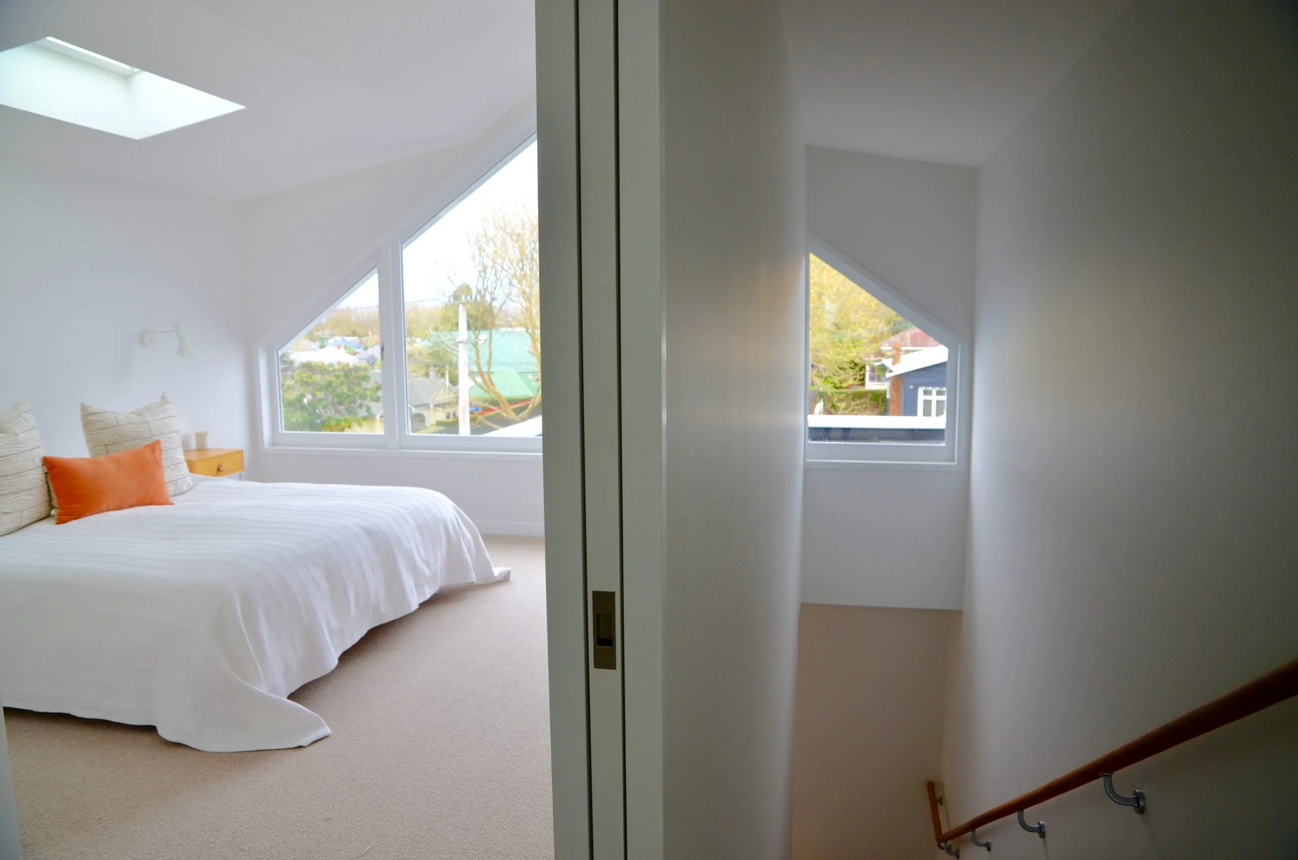 A bedroom with a low bed, soft grey bedlinen and glazing opening onto a balcony.