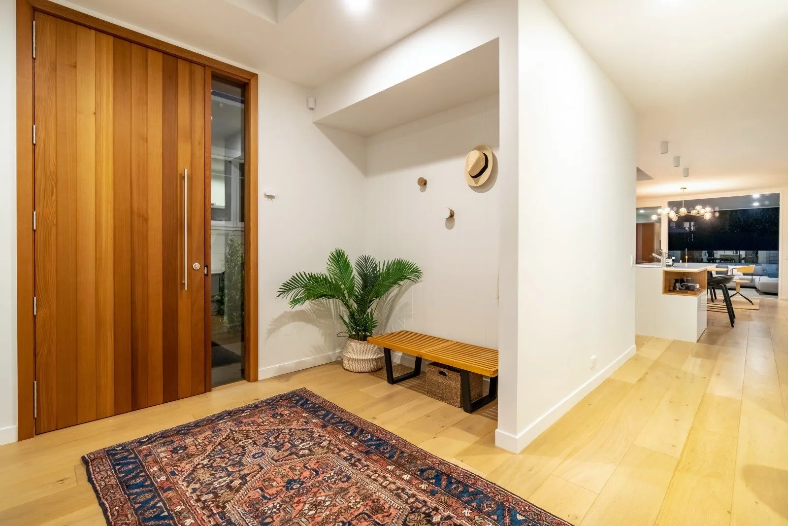 An entry with a solid timber front door, oak flooring and a patterned runner, opening through to the living space.