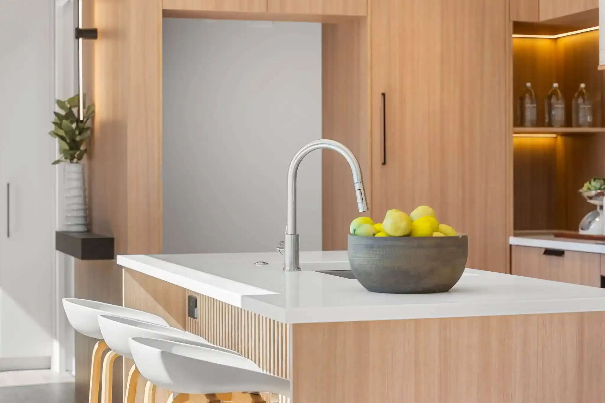 A detail of the island end, showing the fluted timber panelling meeting the white stone benchtop and a tap over the sink.