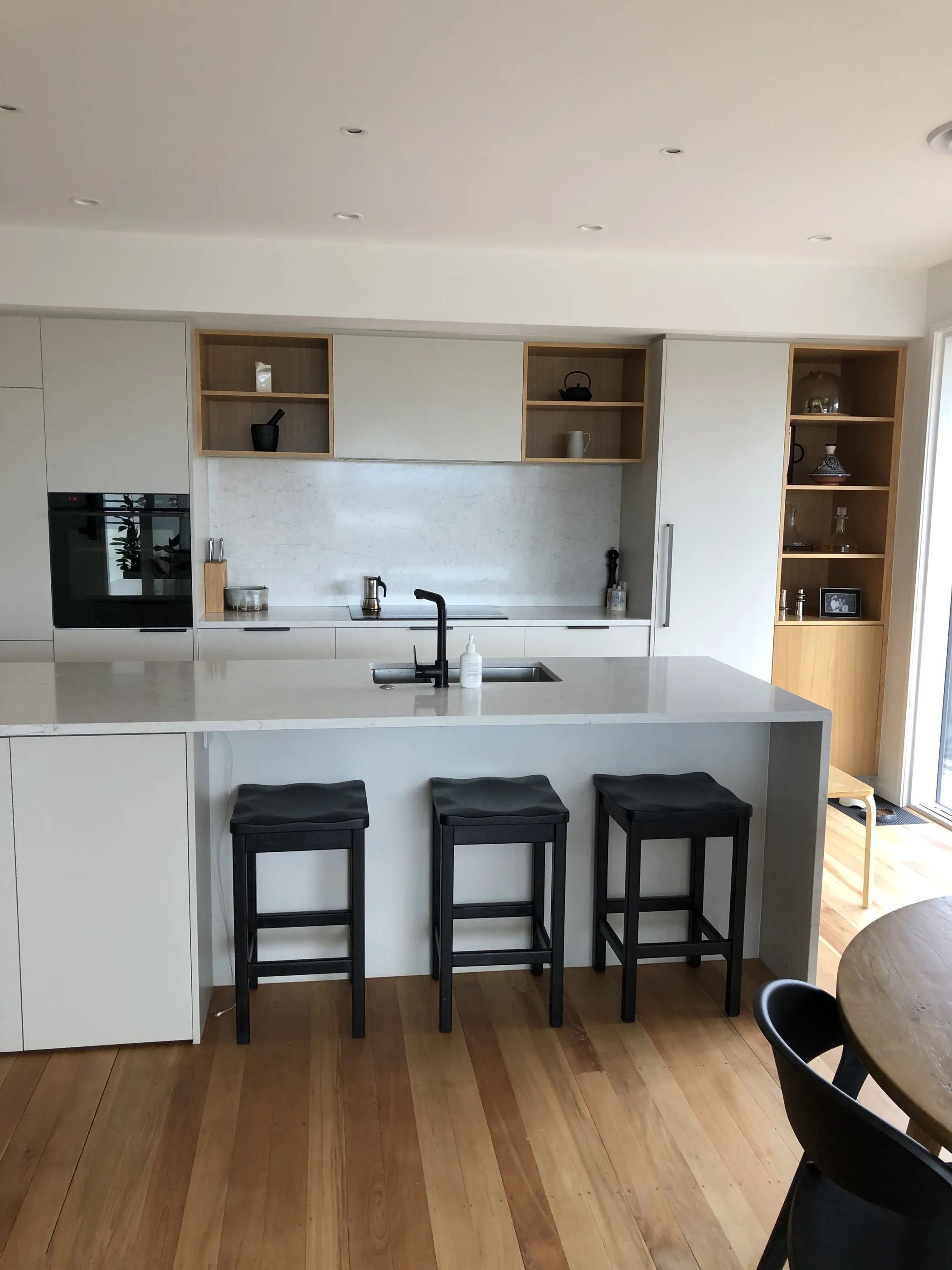 The kitchen from the dining end, showing the full run of white cabinetry and the stone island.