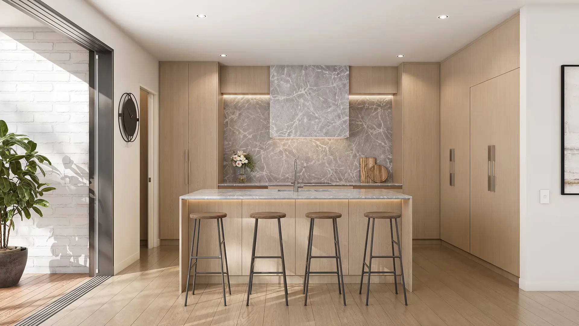 A kitchen with pale oak joinery, a grey marble splashback and hood, and a stone island with stools drawn up to it.