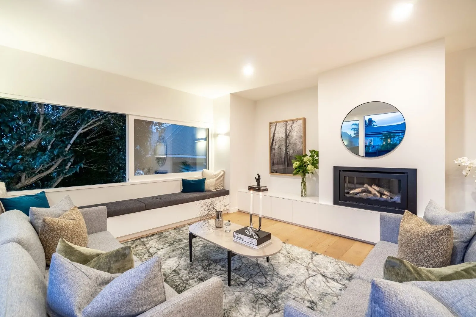 A living room with an inset fire, artwork above it and a pale sectional sofa on a wool rug.